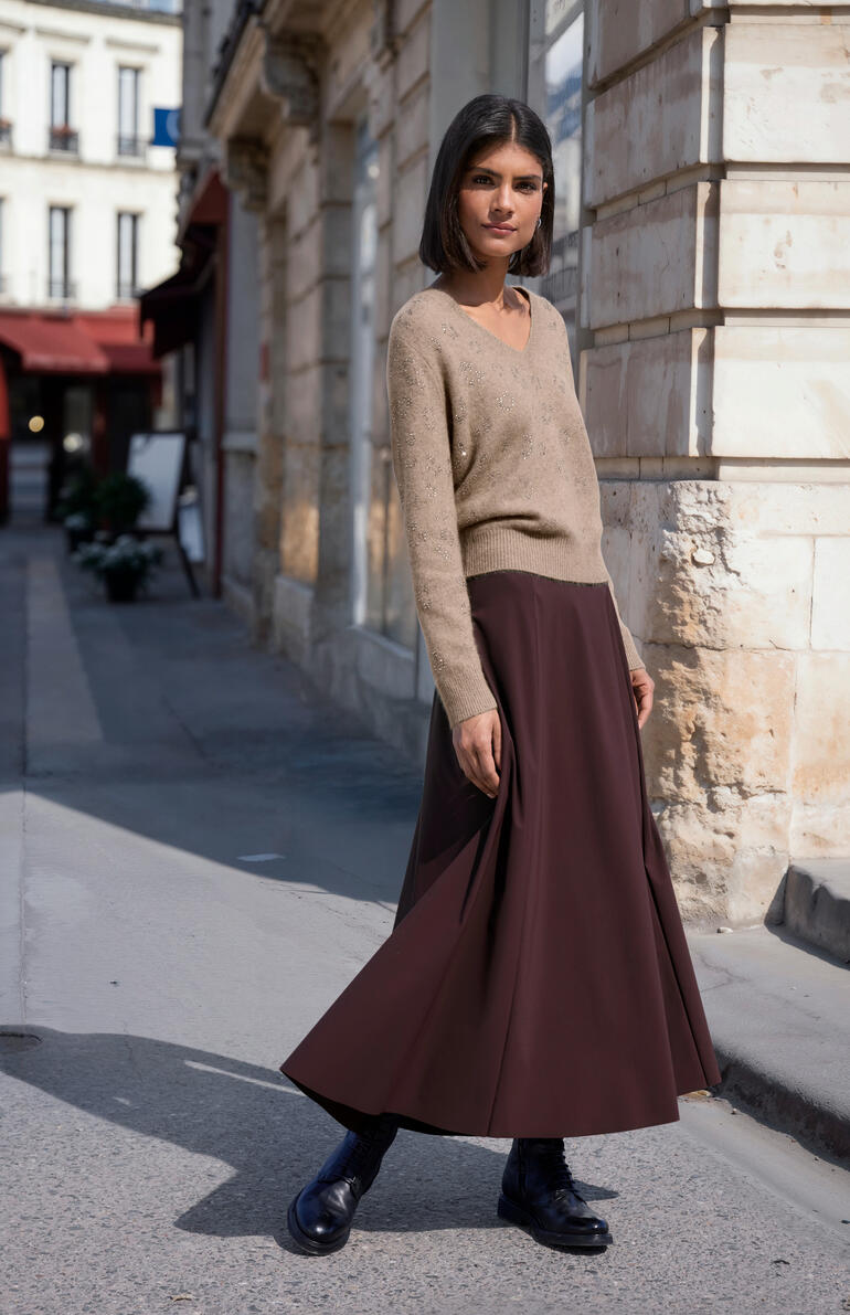 Frau in braunem Flausch-Pullover und Maxiröcken auf einer Straße.