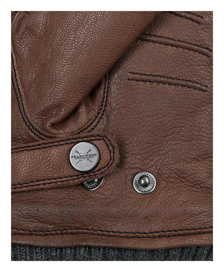Detailaufnahme eines braunen Handschuhs mit Druckknopf.