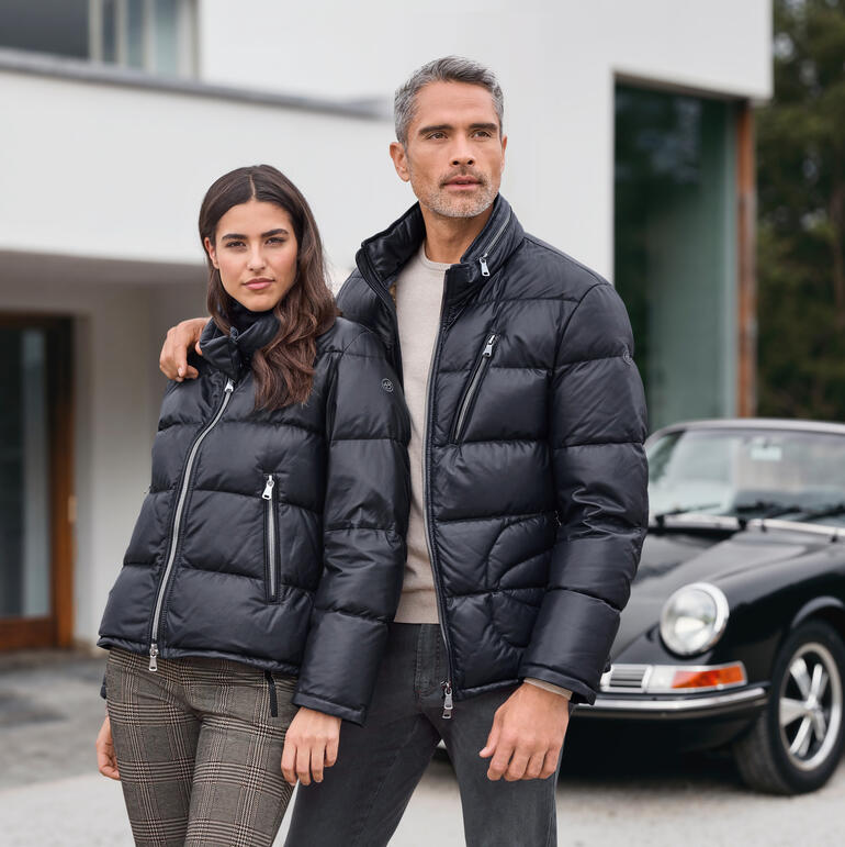 Mann und Frau in schwarzen Daunenjacken, lächelnd.