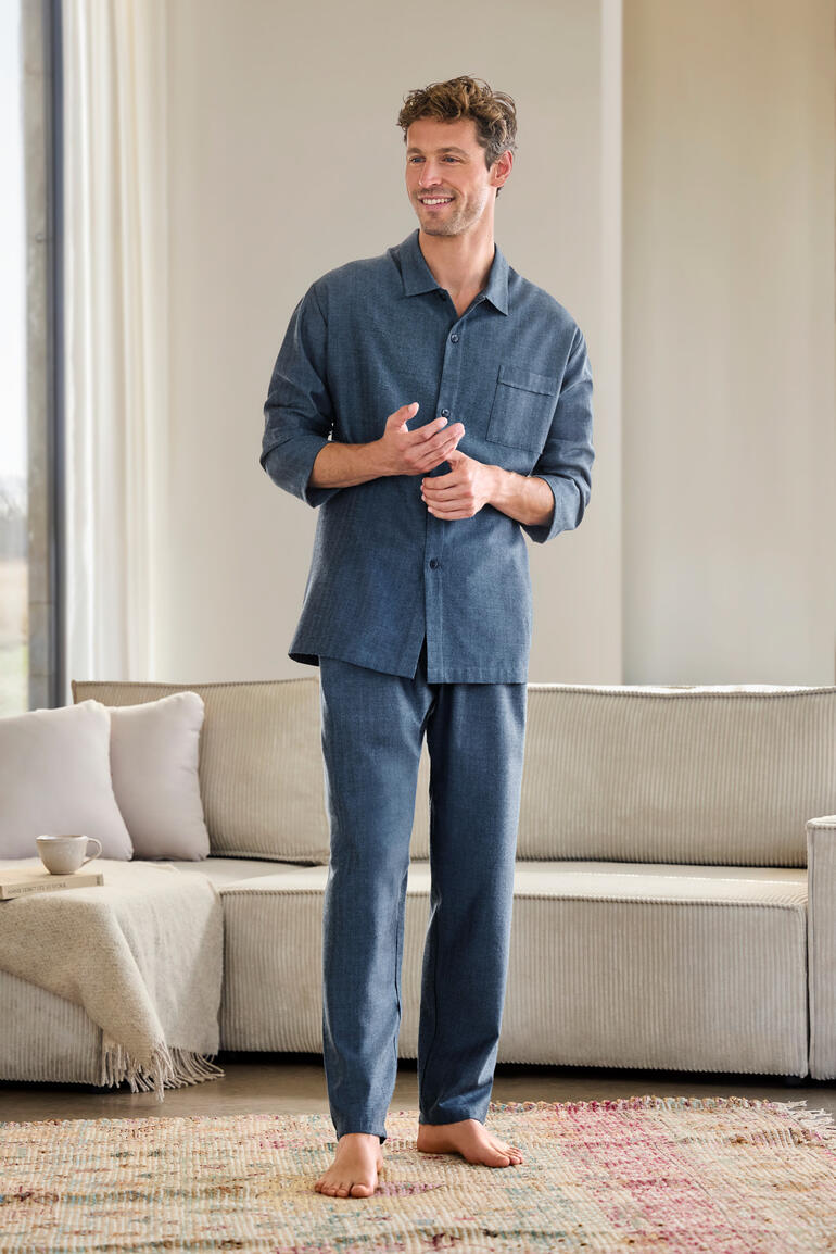 Mann trägt flanellartiges Fischgrat-Pyjama in Dunkelblau mit einer Brusttasche.