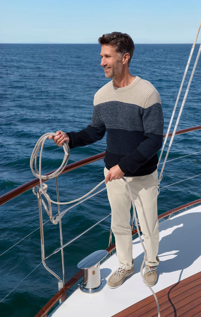 Junghans 1954 Perlfang-Pullover Mann trägt einen perlfang Pullover auf einem Segelboot am Meer