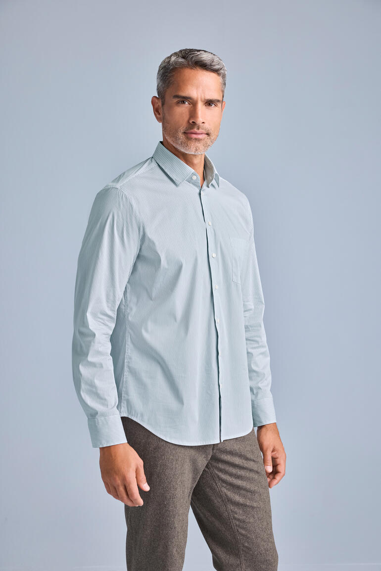 Mann in einem hellblauen Merino-Seiden-Hemd steht in einem Studio.