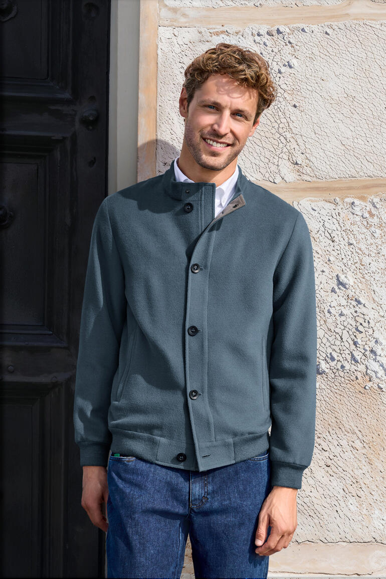 Mann trägt einen blå Brushed-Alpaka-Blouson vor einer Wand.