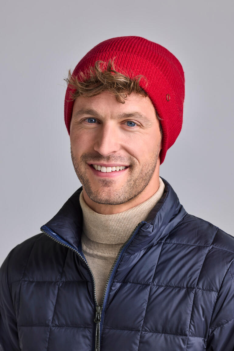 Mann mit roter Kaschmir-Beanie und blauer Jacke.
