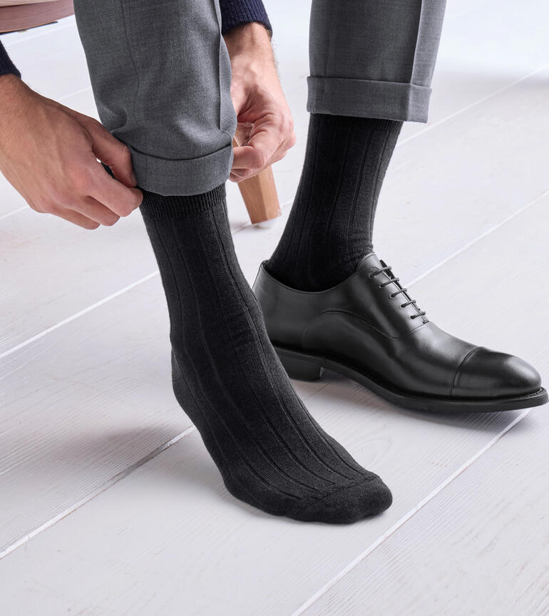 Mann zieht graue Alpaka-Edelsocken an