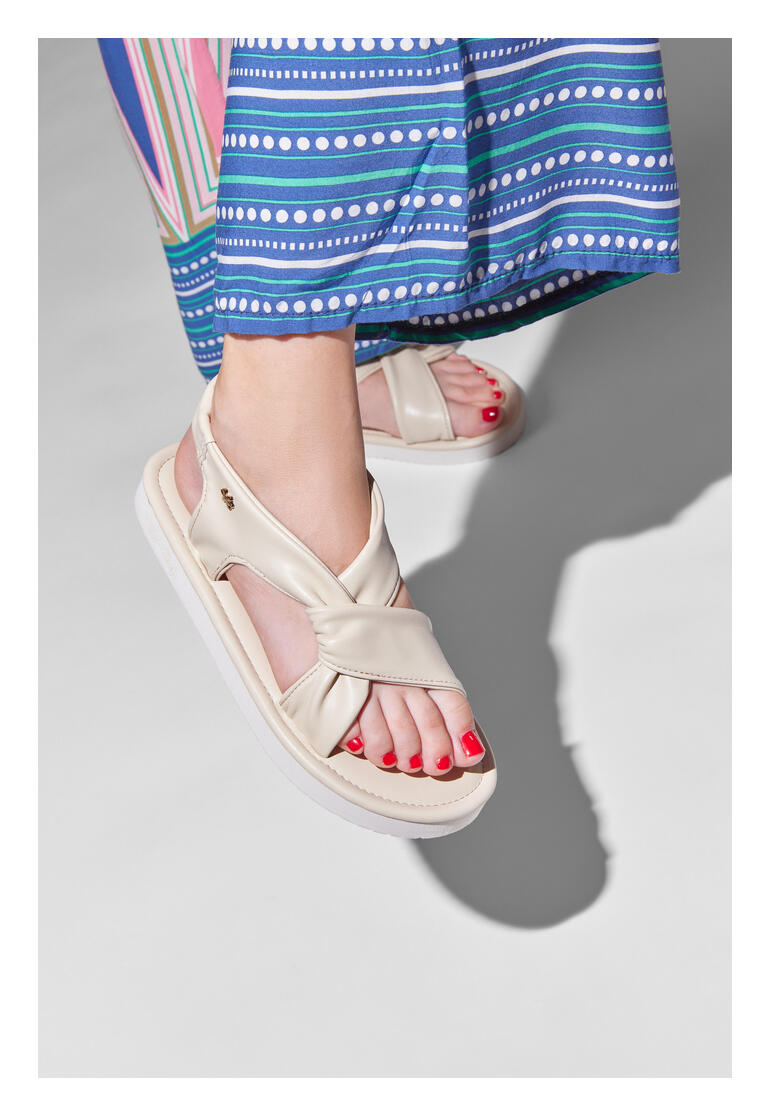 Füße in flip-flop Ultralight-Sandale vanille, Stoffrock im Hintergrund.