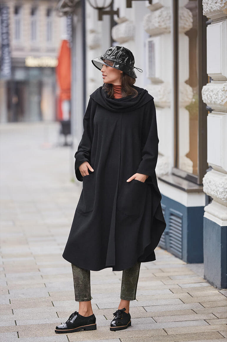 Cape-Mantel Frauenmodel trägt schwarzen Cape-Mantel, steht in der Stadt.