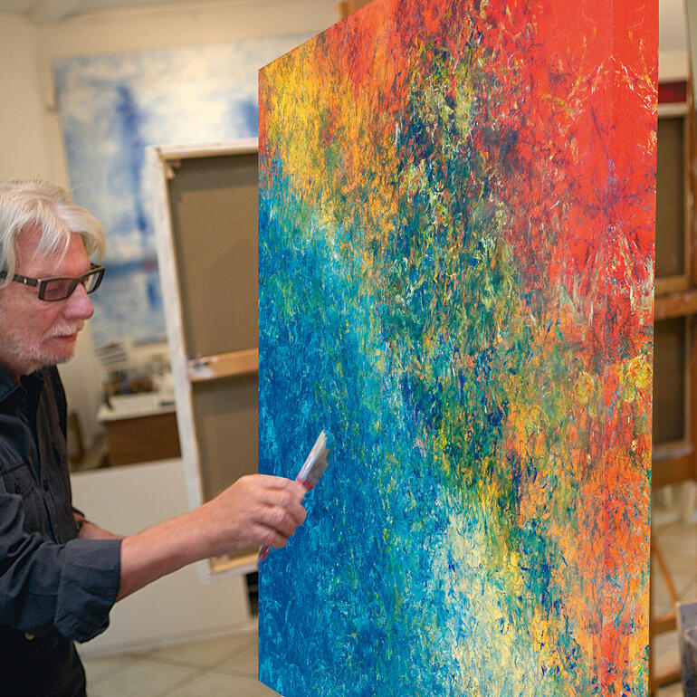 Benno Werth in seinem Atelier. Künstler Benno Werth malt an einem lebhaften, abstrakten Gemälde in seinem Atelier.