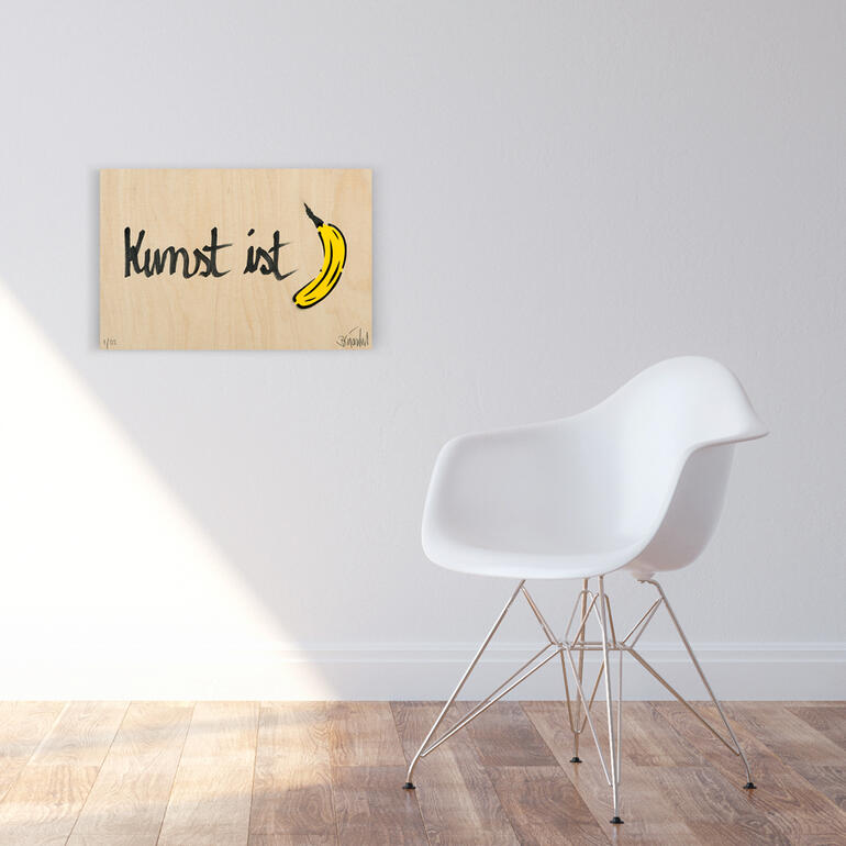 Ein Unikat von Baumgärtel, das zu 100 % von Künstlerhand erstellt ist. Holzplatte mit dem Schriftzug 'Kunst ist' und einer Banane.