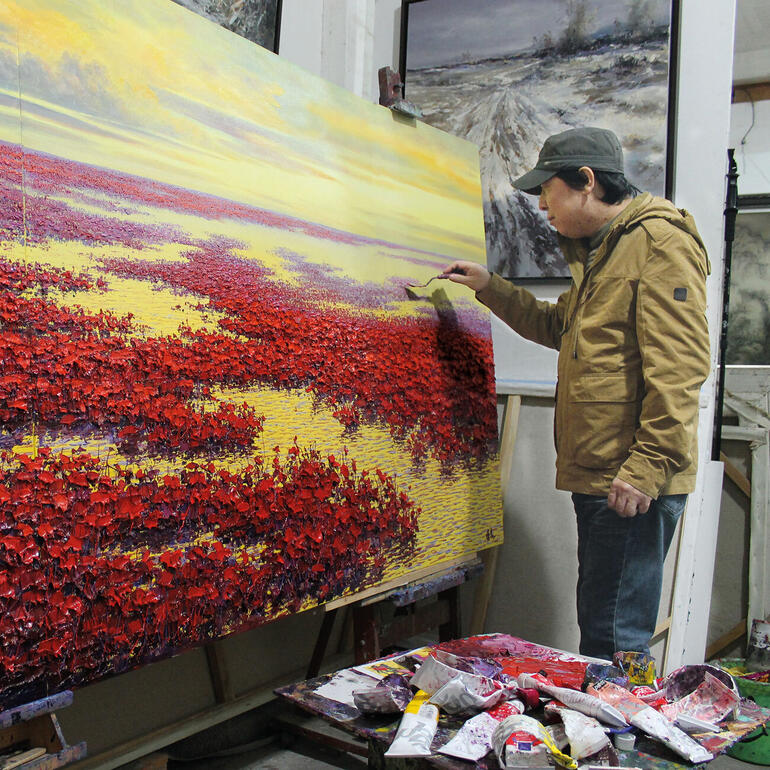 Pei Lian Zhi in seinem Atelier. Künstler malt eine rote Landschaft auf einer großen Leinwand.