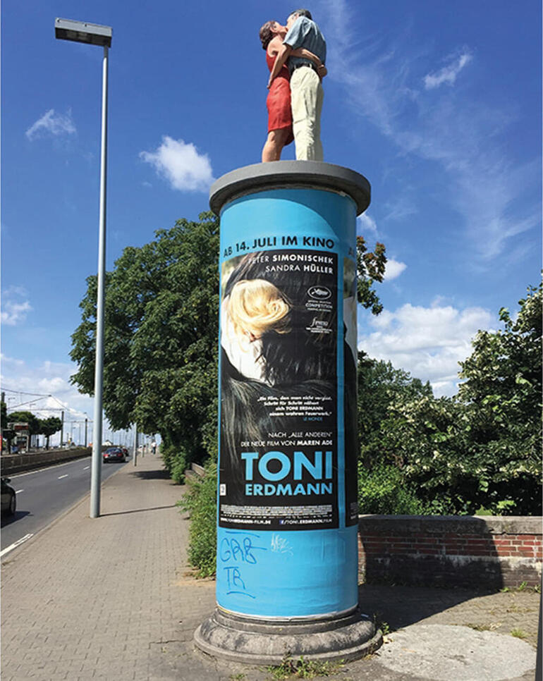 Die 1,90 m große Originalskulptur auf einer Litfass-Säule ist in Düsseldorf zu sehen. Statuette eines Paares auf einer bunten Säule an einer Straßenecke.
