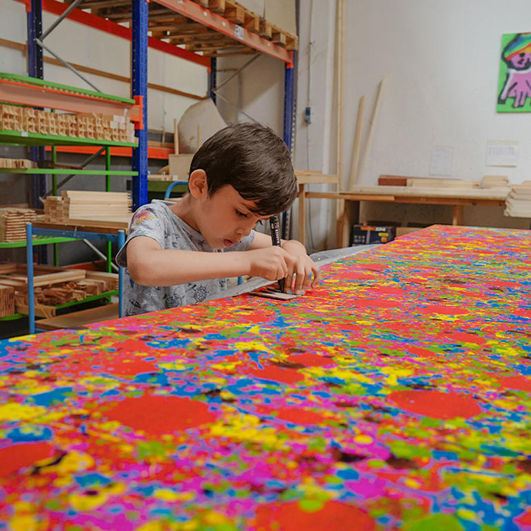 Mikail Akar Junge, die an einem farbenfrohen Kunstwerk arbeitet.