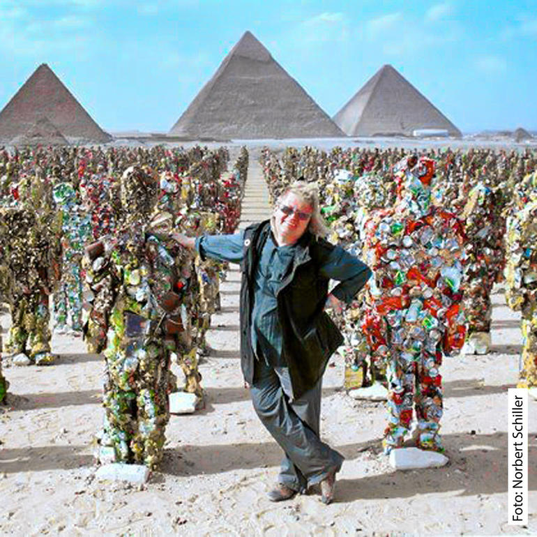 Von den Pyramiden von Gizeh bis zur Arktis, vom Roten Platz bis zur Chinesischen Mauer... Seit über 20 Jahren lässt HA Schult seine Mahnmale weltweit in Reih und Glied stellen. HA Schult posiert mit seiner Trashman-Skulptur in der Wüste