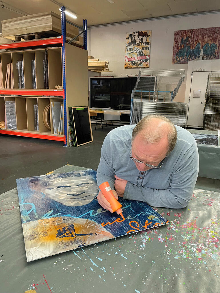 Devin Miles Mann arbeitet an einem Kunstwerk auf einem Tisch im Atelier.