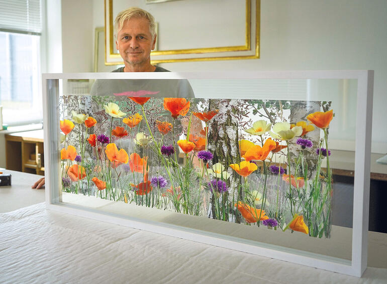 Andreas Lutherer Künstlerin steht hinter einem Kunstwerk mit Blumenmotiven.