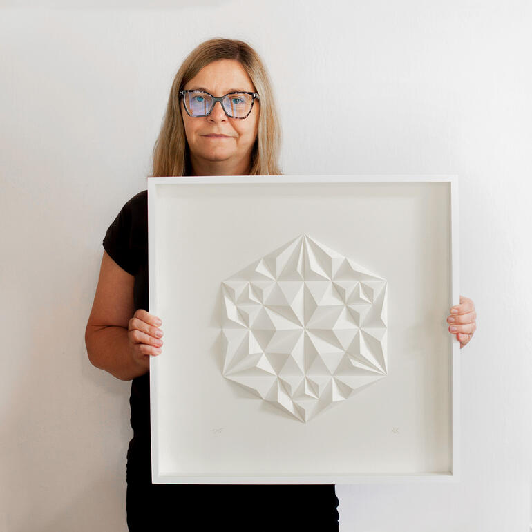Anna Krushelska Frau hält dreidimensionale Papierkunst mit geometrischem Muster