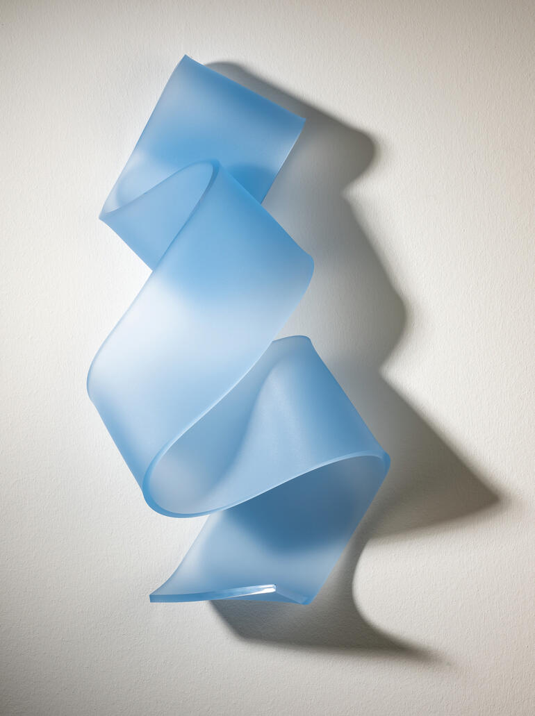 Transparente blaue Kunststofffolie in spiralförmiger Anordnung an der Wand, die den Schatten aufzeigt.