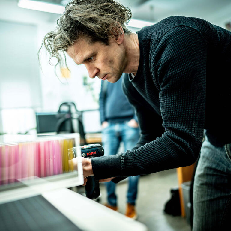 Maxim Wakultschik Mann arbeitet mit einem Werkzeug an einem Druckmaterial.