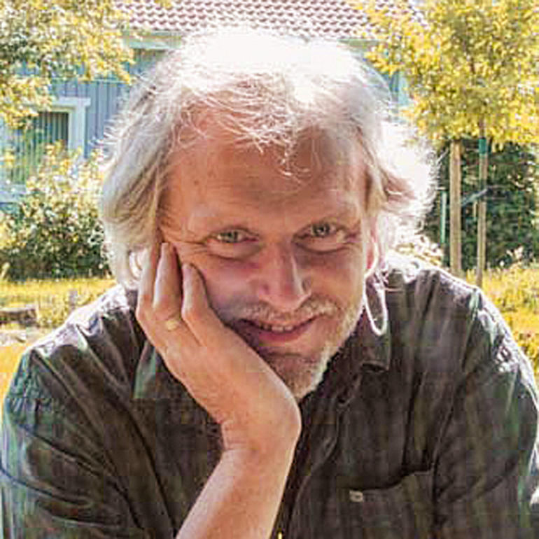 Michael Lauterjung Mann mit grauen Haaren lächelt und stützt sein Kinn mit der Hand.