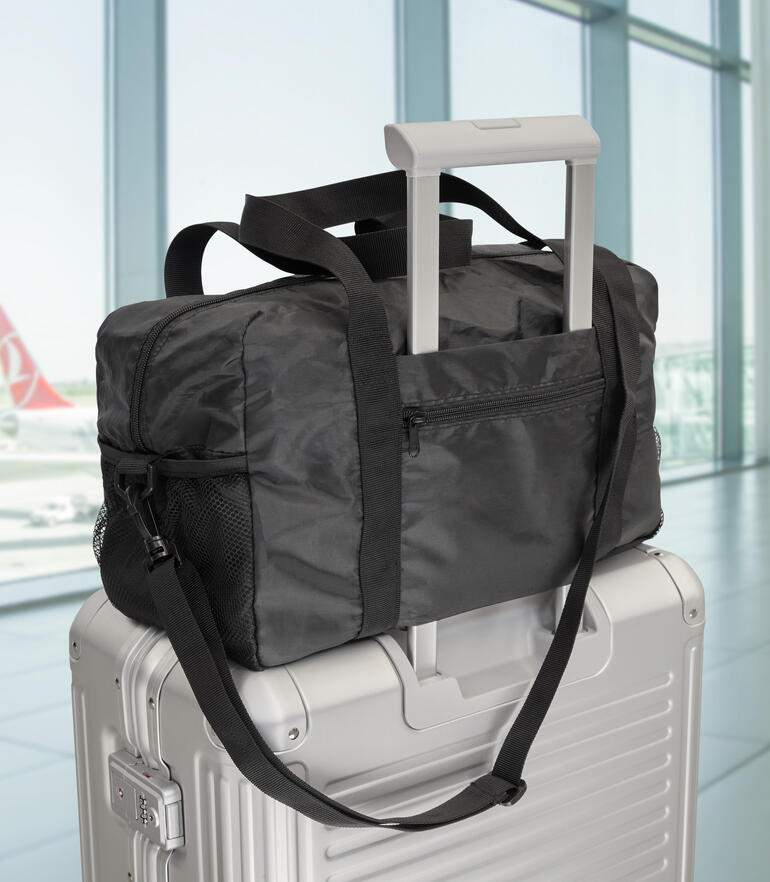 Exklusive faltbare Reisetasche auf einem Koffer im Flughafen.