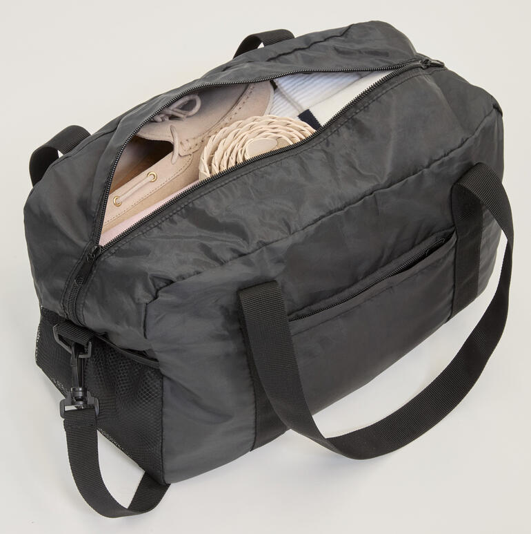 Offene faltbare Reisetasche mit Schuhen und anderen Gegenständen.