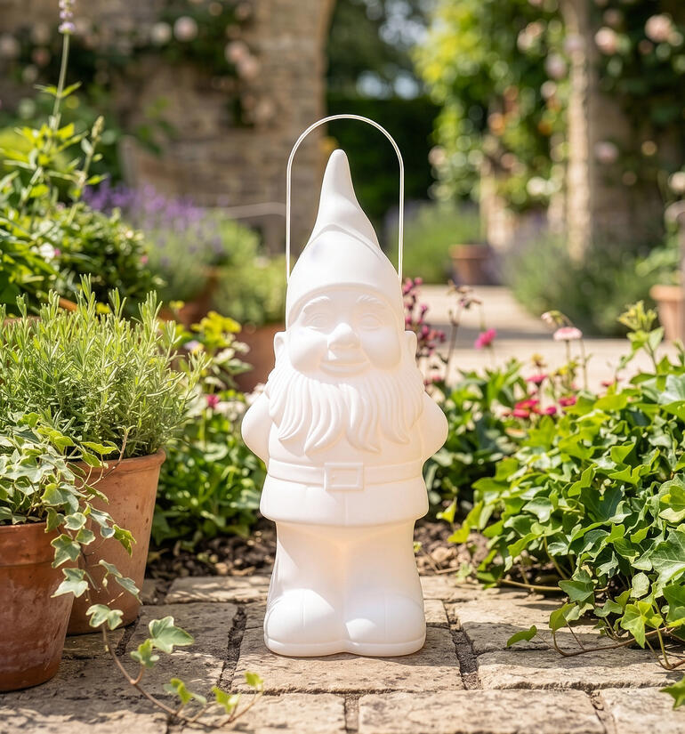 Weißer Gartenzwerg mit einem Eimer in einer blühenden Umgebung