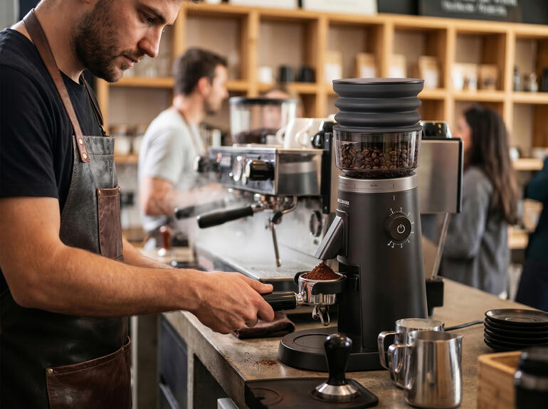 Barista mahlt Kaffeebohnen mit elektrischer Kaffeemühle im Café.