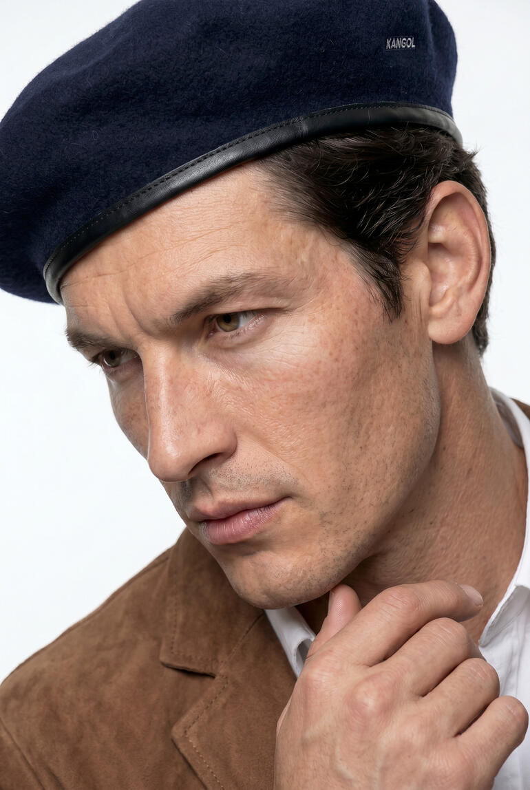 Mann trägt einen Kangol Baret und schaut nachdenklich.