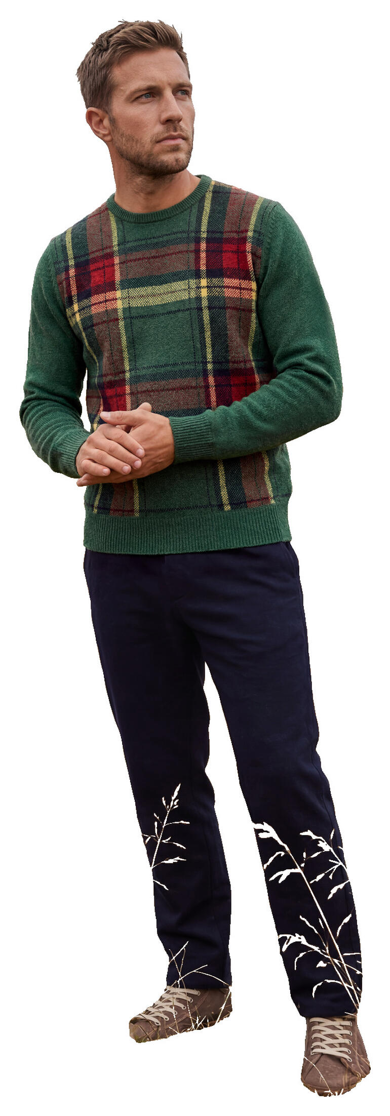 Mann in grünem Tartan-Pullover steht in einer herbstlichen Landschaft.