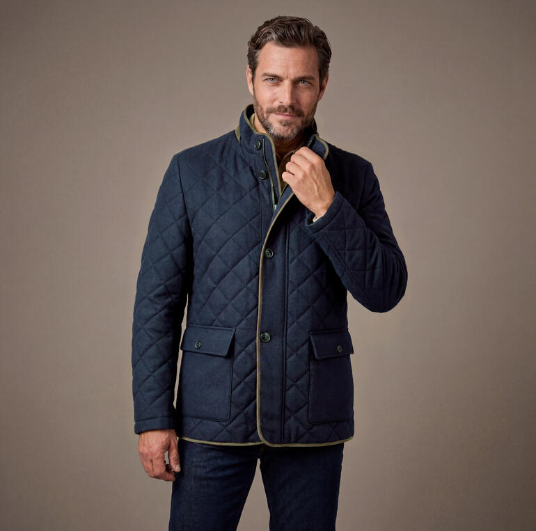 Mann trägt eine dunkelblaue Soft-Loden-Steppjacke mit hohem Kragen und schaut zur Seite.
