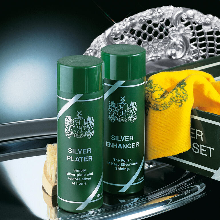 Zwei Flaschen Silberpolitur und ein Reinigungstuch auf einem silbernen Tablett.