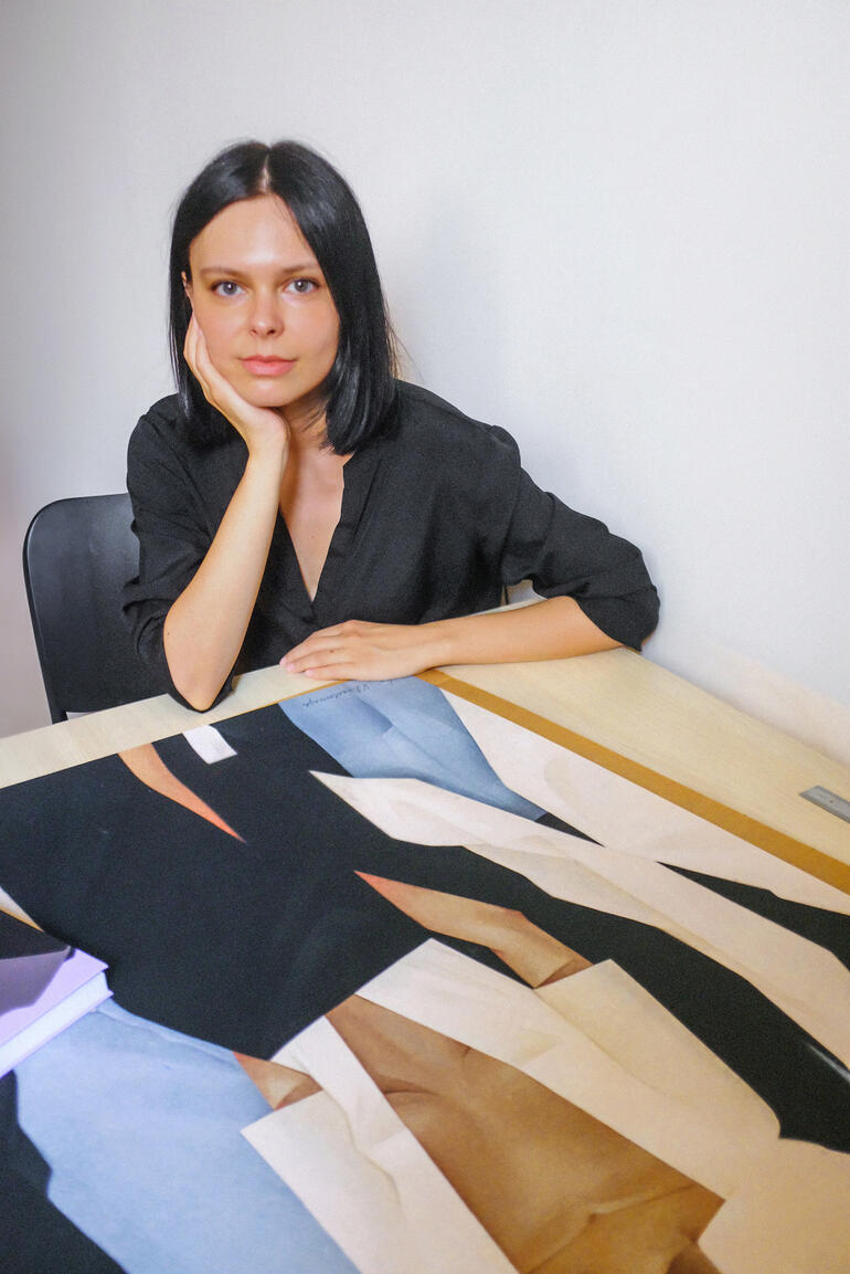 Valeriya Simantovskaya Frau mit langen Haaren sitzt an Tisch, arbeitet an Kunstwerk.