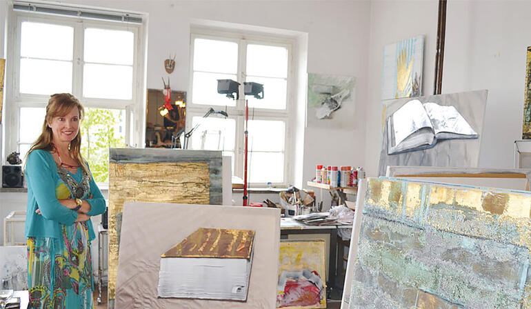 Beatrice Bues-Bohl steht in ihrem Atelier vor mehreren Kunstwerken.