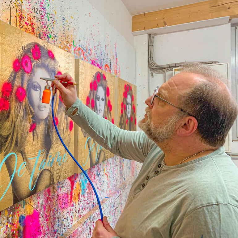 Devin Miles bei der Handübermalung seiner Edition. Devin Miles sprayt Farbe auf ein großes Kunstwerk mit dem Titel 'Je t’aime'.