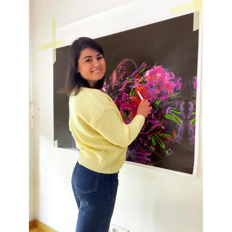 Yuliya Grzmehle zeichnet mit einem Pinsel an einer großen Leinwand.