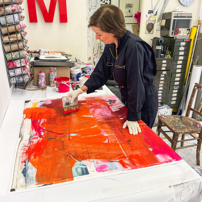 Manuela Karin Knaut arbeitet konzentriert an einem Kunstwerk mit orangefarbener Farbe.